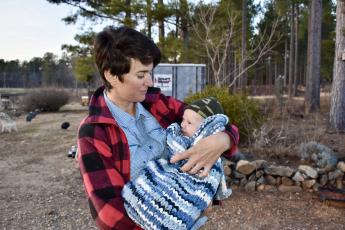 Laura Pallas, who co-owns Buffalo Creek Berry Farm and has a doctorate in food science from the University of Georgia, holds her son Arthur James Phillips in February 2022. Pallas uses leftover produce in a manner of ways, including syrups and jams. (Kate Hoffman/The Oglethorpe Echo)