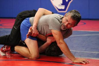 OCHS wrestling coach Tim Stoudenmire teaches his team a new move with help from senior Tanner Mask. Stoudenmire said there are more experienced wrestlers on this year’s team than last year. (LAUREN HILL/THE OGLETHORPE ECHO)