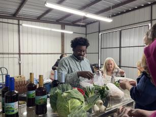 Kendall Strickland, owner of Strickland Pride Produce, sells vegetables at the grand opening of his store's new Crawford location on Feb 5. About 50 people attended the ribbon cutting to shop his selection of fruits, vegetables and other goods. (Margaux Binder/The Oglethorpe Echo)