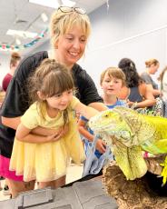 Brooke Shook shows her children, Sonny Shook (left) and Copeland Shook,  an iguana at The Oglethorpe County Library's reptile encounter on June 9. A total of 162 people were in attendance, which is a record for that event. (Submitted Photo)