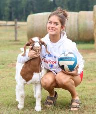 Naomi McPeake smiles with her goat, Sexy Red, and a volleyball at her family farm in Crawford. She balances her two passions, volleyball and showing goats, with the help of her family. (SYDNEY JARRARD/THE OGLETHORPE ECHO)