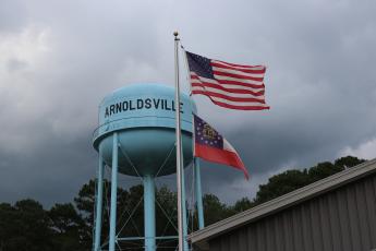 Flags wave in front of the Arnoldsville water tower located outside the city's courthouse on Aug. 21, 2025. (Photo/Mia Fishman)