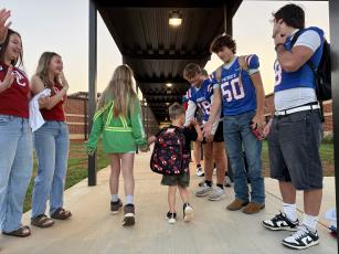 An OCES student high-fives OCHS football player Lance Ellefson as another OCES student guides him through the Patriot Pride drop-off line. “When it started, we figured, let’s just have this amount of players come out, this amount of cheerleaders come out. Now it’s more that they all want to be a part of it,” said athletic booster club president Janine Campbell about the growing popularity of the Patriot Pride Drop-off.