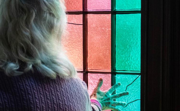 Evelyn Reece touches the interior of a stained glass window in the former Lexington Presbyterian Church earlier this month. The windows were recently restored with the help of funds received from a grant written by Reece. (Photo/Sarah White)