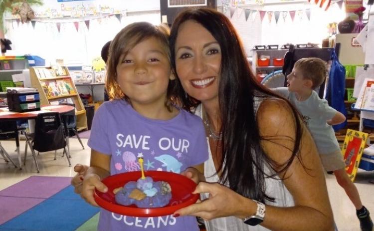 Penni Stoudenmire smiles in her classroom with one of her Kindergarten students after an in-class activity. Stoudenmire uses hands-on activities like this one to foster an enjoyable and engaging environment for her students. (Submitted Photo)