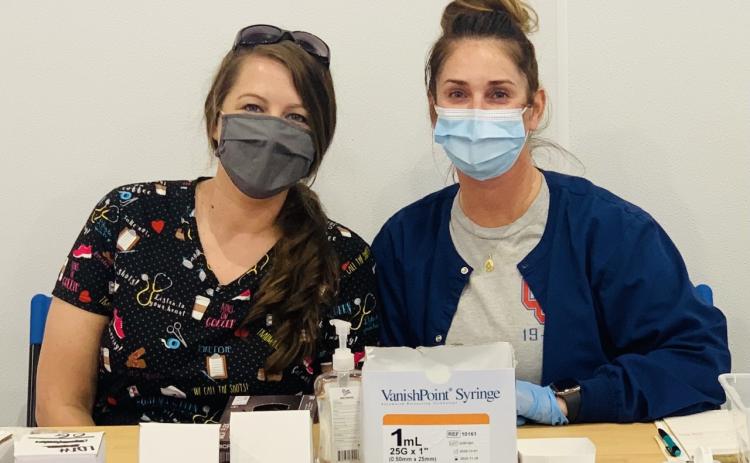 Erin Bunch (left) and Kristina Turner wear their masks while they work at a vaccine clinic. (Submitted Photo)