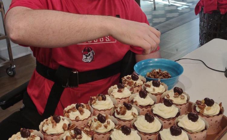 Dillon Lewis places chopped pecans on his chocolate pecan delight cupcakes. The Lewis family is proud of where D-Lo’s stands and doesn’t feel pressure to grow the business. (Submitted Photo)