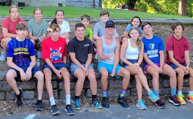 Members of the cross country teams sit for an impromptu team photo in front of the courthouse. (Submitted Photo)