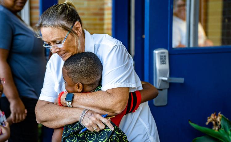 Sandra Wheeler, the bookkeeper and registrar at Oglethorpe County Primary School, hugs a student as children head back to school on Tuesday. (Photo/Jack Casey)