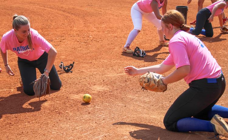 (De Turner/The Oglethorpe Echo) Senior Claire Gabriel, left, and junior Abby Jones work on a fielding drill together during practice. The pitcher and catcher have played together for several years.