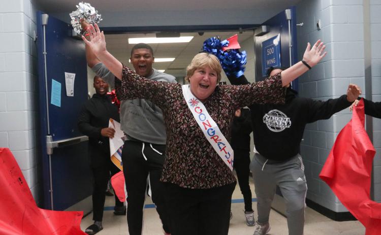 Beverley Levine runs through a paper banner upon entering Oglethorpe County High School as part  of her celebration through the county schools. (Photo/Katie Tucker)