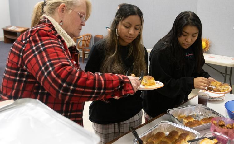 Sherry Lipinski (left) puts food on the plates of Alyssa (middle) and Chelsea Durie during the Oglethorpe County Library’s first Friendsgiving on Nov. 15. About a dozen teens participated in the event. (Katie Tucker/The Oglethorpe Echo)