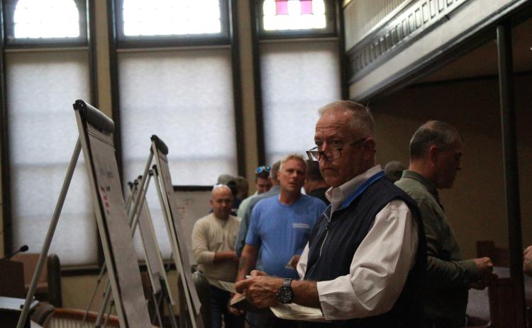 Firefighters place numbered stickers on large pads of paper to indicate their station's priorities during a meeting in the Oglethorpe County courthouse in Lexington, Georgia, on Monday, Oct. 17. (Emily Garcia/The Oglethorpe Echo)
