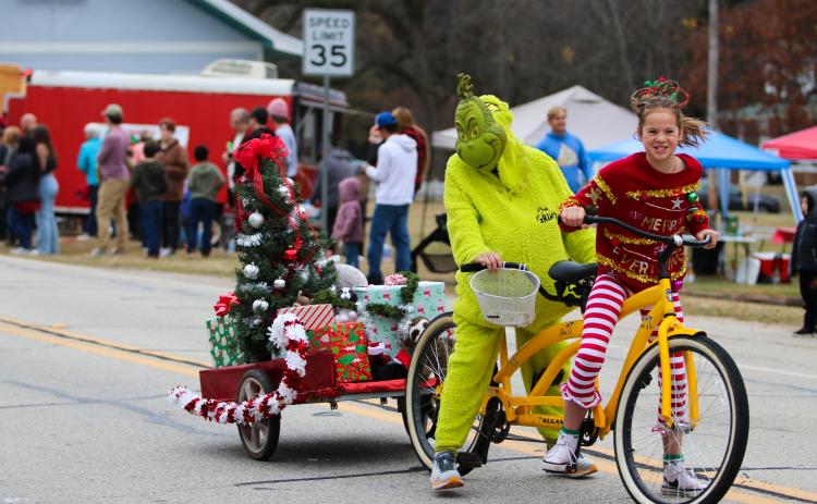 The Grinch rides in tandem with Christmas cheer, throwing candy  at those lining the street at the Maxeys Christmas Parade.