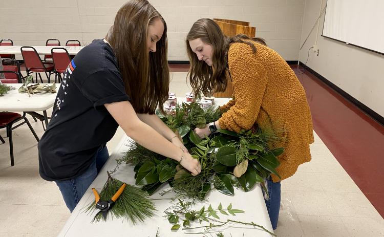 Callie Bridges (left) and Andee Dellinger work on an example wreath at a wreath making class on Dec. 8. The students are both OCHS freshman who are taking the floral design class. (Erin Kenney/The Oglethorpe Echo)