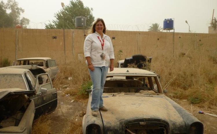 (Submitted Photo) Gina Holloway, standing on top of an abandoned vehicle in the Green Zone in Baghdad in 2011, managed a sign shop in Iraq even though she didn’t speak Arabic.