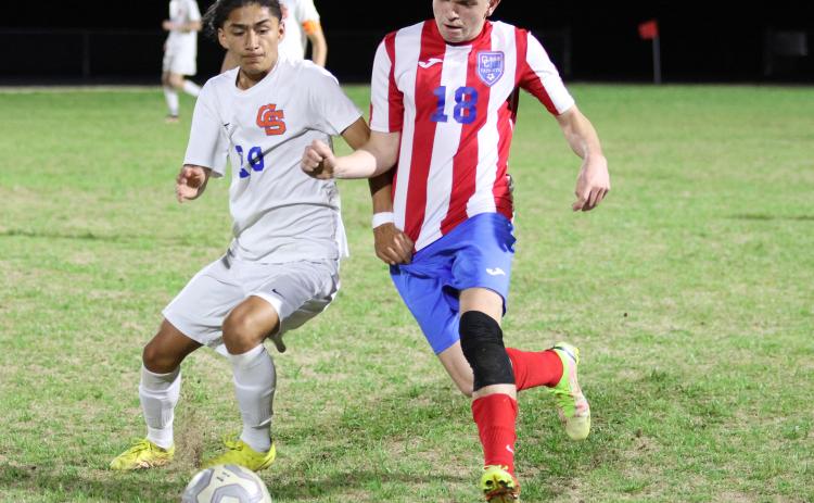Oglethorpe County senior Soren Wisby (right) battles a Cedar Shoals player for possession during Oglethorpe County's 5-0 loss at Cedar Shoals last Tuesday. The Patriots will host Mount Vernon in the first round of the Class A Division I tournament on April 12. (Photo/Emily Dozier)