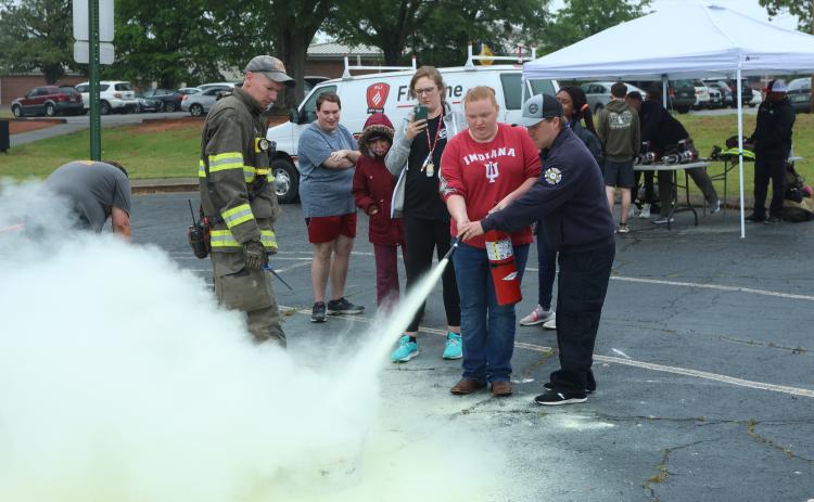 First responders Cody Gibbs (from left) and Matthew Echols help Oglethorpe County High School student Kayla Bass practice with a fire extinguisher. Gibbs recently won AEMT of the Year at the Region 10 EMS Banquet. (LANDEN TODD/THE OGLETHORPE ECHO)