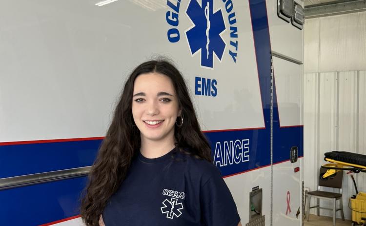 Kate Spearing, a 2023 Oglethorpe County High School graduate, stands with a county ambulance in her emergency medical services uniform. Spearing has logged more than 200 clinical hours as an EMT and will compete at HOSA’s International Leadership Conference in Dallas starting June 21. (McCain Bracewell/The Oglethorpe Echo)