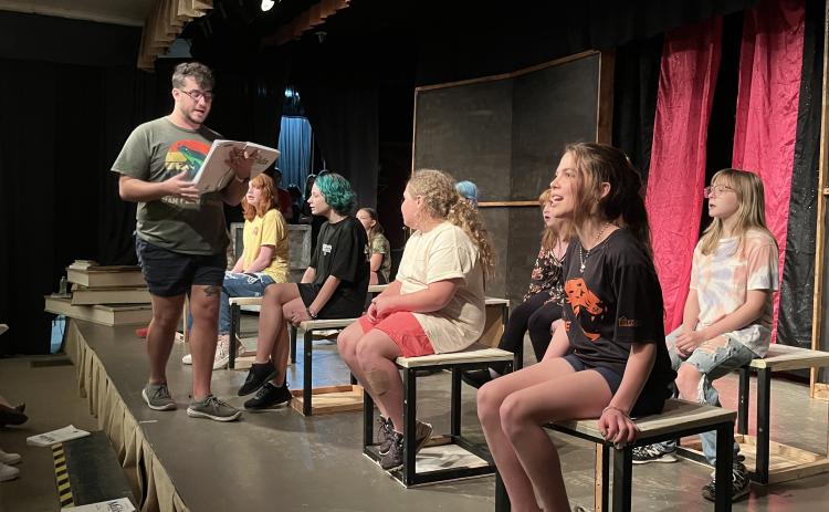 Music director Chase Cooper leads the cast of Matilda the Musical during a rehearsal on June 10 at the Historic Crawford School. Left to right are Ellie Roman, Hazel Hogan, Allie Spurlin, Thalia Smoot and Kassie Mathews; obscured are Jenna Grace Burt, Clover McGovern and Sophia Priest. Arts!Oglethorpe director Bly Hartley said the production’s actors have a wide range of ages, and the show is family-friendly. (JESSE WOOD/THE OGLETHORPE ECHO)