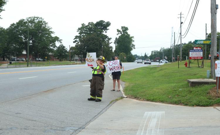 Robert and Lani Kline hold signs on Highway 78 to let folks know about the Wesley Chapel Volunteer Fire Department’s car wash fundraiser at Lexington Auto Parts last Saturday. The donations help the department purchase and maintain its equipment. (LANDEN TODD/THE OGLETHORPE ECHO)