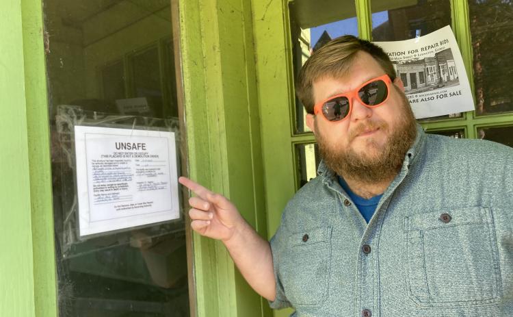 Glynn Segars, owner of Community Cigar and member of the Lexington Downtown Development Authority, points out the notice on the window in a building along Main Street in downtown Lexington. “It’s a concern for public safety, it’s a concern for business development and it’s a concern for historic preservation,” he said.