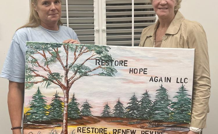 Miriam Pledger (left), founder of Restore Hope Again, holds a painting of the support group’s logo with Patricia Shelton (right), a member of the administration team. Restore Hope Again is a Christian-based support group in Oglethorpe County.