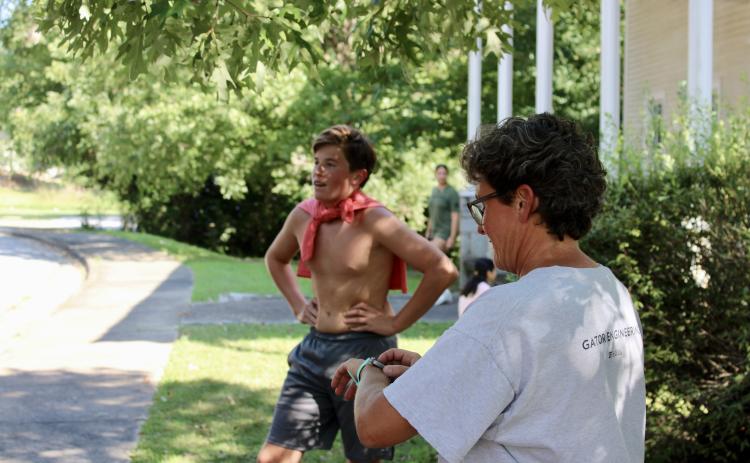 Head coach Jessica Ward checks the time as the first runner, freshman Dylan Minthorn, returns from his run at practice on Thursday, Aug. 22, 2024. The team rotates practice routes during the season to gain experience on different surfaces and with differing millage. (Audrey Pfitzner/The Oglethorpe Echo)