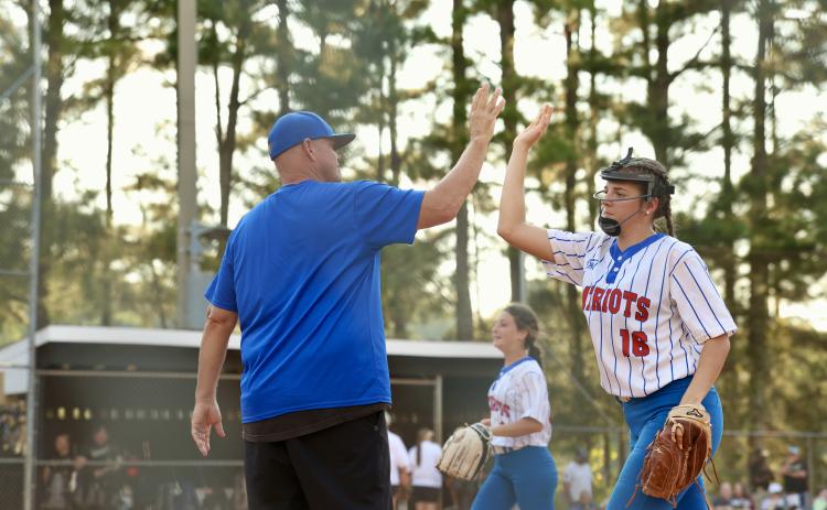TY JOHNSTON/THE OGLETHORPE ECHO OCHS softball assistant coach Mike Campbell high-fives Lillie Anderson during the Patriots’ 10-2 win over Commerce on Tuesday. Anderson had two hits and an RBI as part of the 15-hit attack.