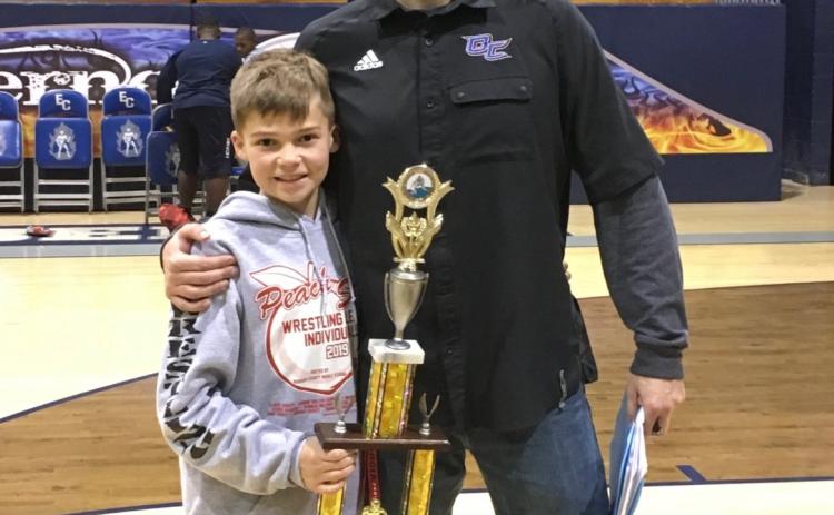 Miles Mason stands with his dad, Steve Mason, after a wrestling match. Steve coached Miles for five years of his career. (Submitted photo)